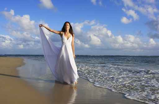 Young woman in white dress on a beach